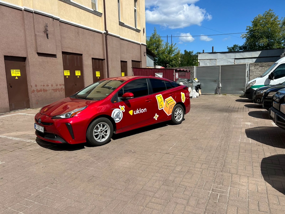 Червона Toyota Prius з брендуванням Uklon на подвір'ї в Києві